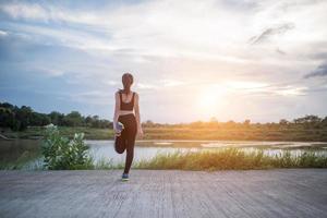 Mujer joven sana calentando al aire libre para entrenar foto