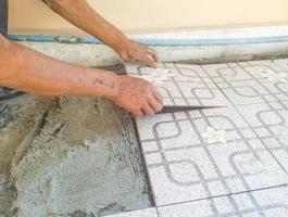 The worker's hand is putting tiles adhesive photo