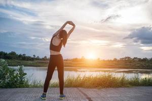 Mujer joven sana calentando al aire libre para entrenar foto