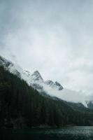 Mountain, lake, and trees with cloudy sky photo