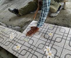The worker's hand is putting tiles adhesive photo