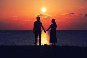 Two people holding hands at sunset