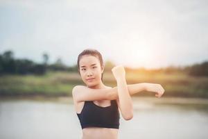 Mujer joven sana calentando al aire libre para entrenar foto