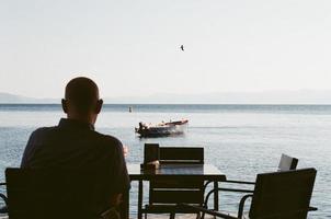 Man in black shirt sitting on brown wooden bench photo