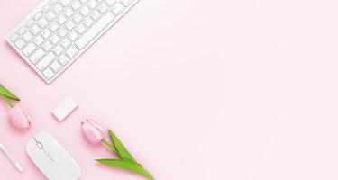 mesa de escritorio de oficina mínima con teclado, mouse, bolígrafo blanco, flores de tulipán, borrador en una mesa rosa pastel con espacio de copia para ingresar su texto, composición del lugar de trabajo de color rosa, endecha plana, vista superior