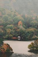 Lake District, Reino Unido, 2020 - Casa blanca y negra cerca del lago rodeada de árboles verdes y marrones durante el día foto