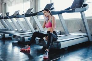 Asian women hold flask, sit and rest tired on the treadmill. photo