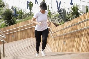 Mujer corriendo con una camiseta blanca, trabajando en una escalera de madera foto