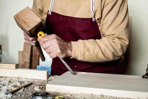 Carpenter's hands with chisel on the woodworking bench photo