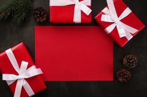 Maqueta de tarjeta de felicitación roja en blanco con adornos de regalo de Navidad sobre fondo grunge
