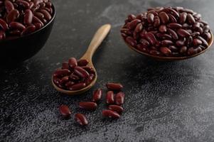 Red beans in wooden bowls on black kitchen surface photo