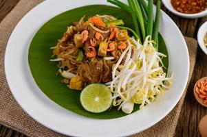 Pad Thai with lemon, eggs and seasoning on a wooden table photo