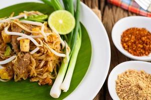 Pad Thai with lemon, eggs and seasoning on a wooden table photo