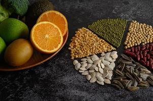 Legumes with oranges, kiwi, and apple on a black background photo