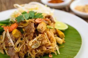 Pad Thai with lemon, eggs and seasoning on a wooden table photo