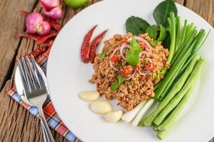 Spicy minced pork salad on green vegetables photo