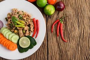 Ensalada de cerdo picada con especias sobre una mesa de madera foto