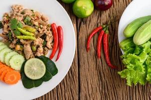 Ensalada de cerdo picada con especias sobre una mesa de madera foto