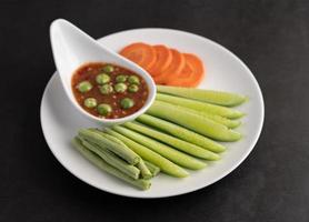 Shrimp-paste sauce in a bowl with cucumber, yard long bean and carrots