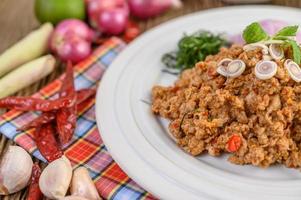 Ensalada de cerdo picada con especias sobre una mesa de madera foto