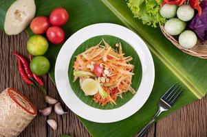 Thai papaya salad with banana leaves and fresh ingredients photo