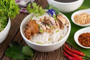 Chicken and noodles in a bowl with side dishes photo