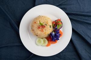 Arroz frito con huevo en un plato blanco con tela arrugada foto