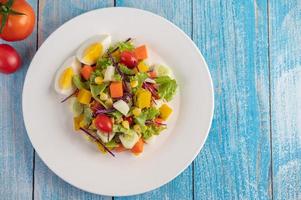 Ensalada fresca en un plato blanco con un sándwich y tomates foto