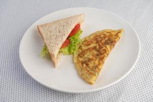 An egg omelette and sandwich on a white plate photo