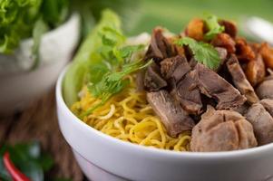 Yellow noodles with crispy pork and meatballs photo