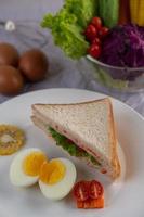 Boiled eggs, corn, tomato sandwich on a white plate photo