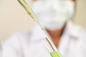 Scientist wearing mask and gloves showing beakers with vaccines photo