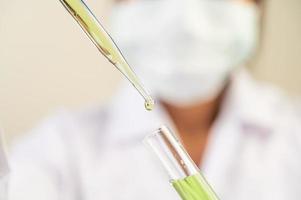 Scientist wearing mask and gloves showing beakers with vaccines photo