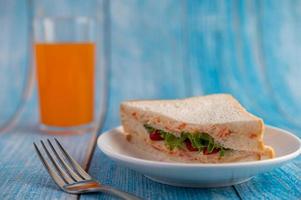 Sándwiches y jugo de naranja en la mesa de madera azul foto