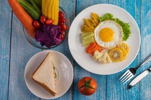 Fried egg breakfast with egg, salad, pumpkin, cucumber, carrot and corn photo