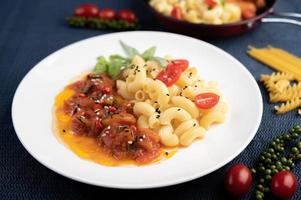 Macaroni dish with with tomato, chili, pepper seeds and basil photo