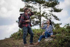 Young couple looking at map while hiking in the forest photo