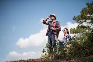 Young couple looking at map while hiking in the forest photo