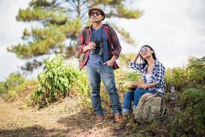 Young couple looking at map while hiking in the forest photo