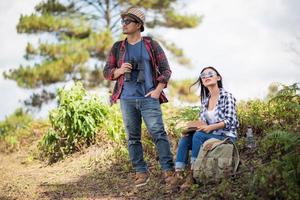 Young couple looking at map while hiking in the forest photo