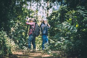 Young couple walking with backpacks in forest photo