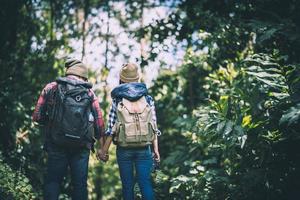 jóvenes viajeros activos tomados de la mano mientras caminan en el bosque