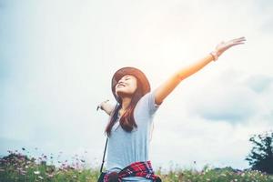 Happy young woman raising her hands in a meadow photo
