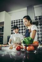 Linda niña y mamá en delantales aplanar la masa en la cocina de casa foto