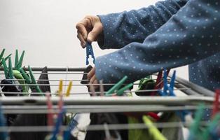 A close-up shot of a human being hanging their newly washed clothes with the help of the colorful clothes clippers photo