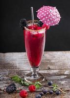 Forest fruit cocktail in a glass on a wooden base decorated with blackberries photo