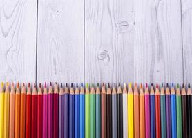 Lápices de madera de colores vistos desde arriba sobre un fondo de madera gris y blanco foto