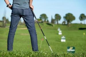 Jugador de golf con gorra recostada sobre un palo de golf mirando el curso foto