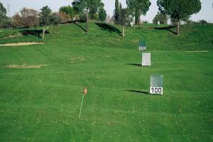 Vista panorámica de un campo de práctica de golf con señales de metros alcanzados.