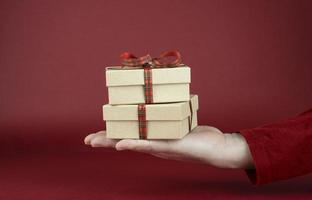 Man's hand holding Valentine's Day gift boxes in front of a red background photo